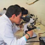 Joven aprendiendo a utilizar el microscopio