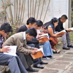 Adultos estudiando con libros al aire libre