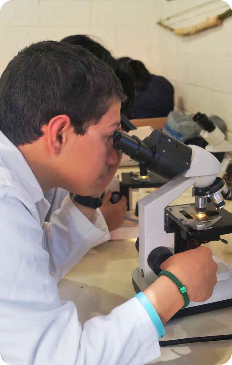 Joven aprendiendo a utilizar el microscopio